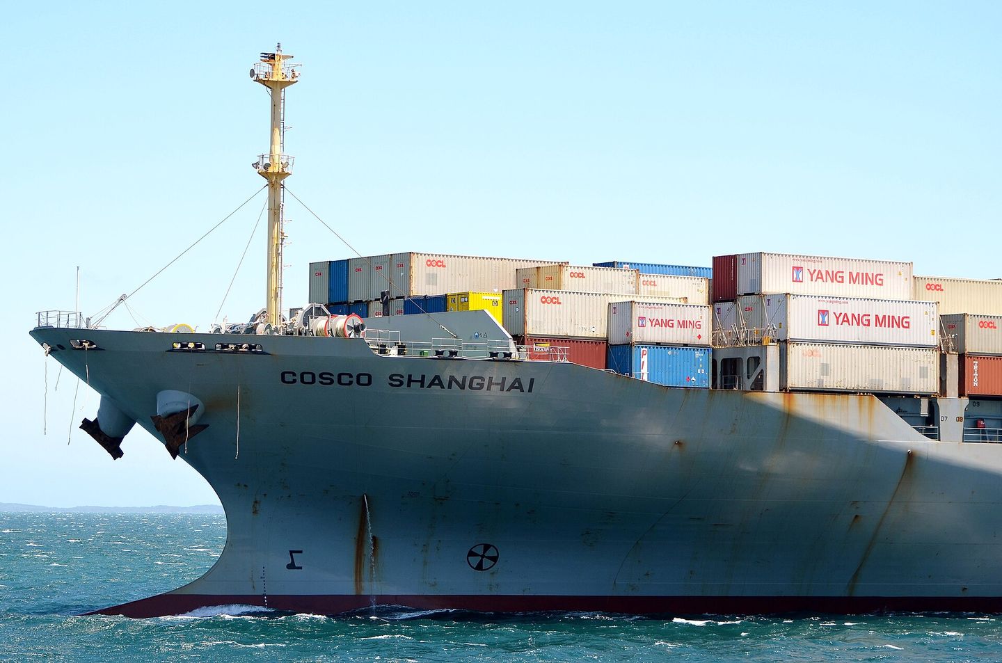 The bow of the container ship COSCO Shanghai, containers stacked high above her deck.