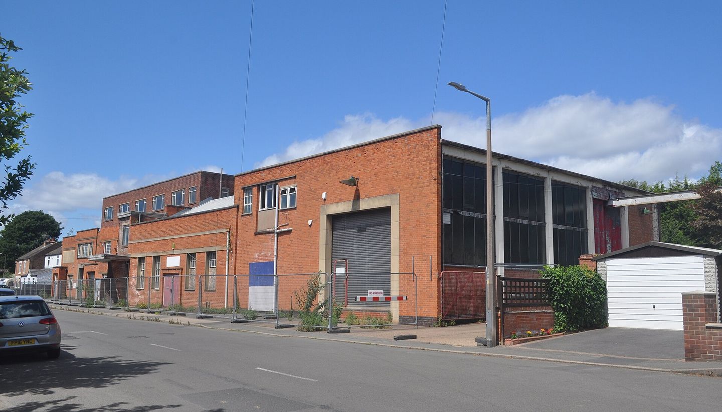Un bâtiment industriel en brique, vide, dans une rue déserte.