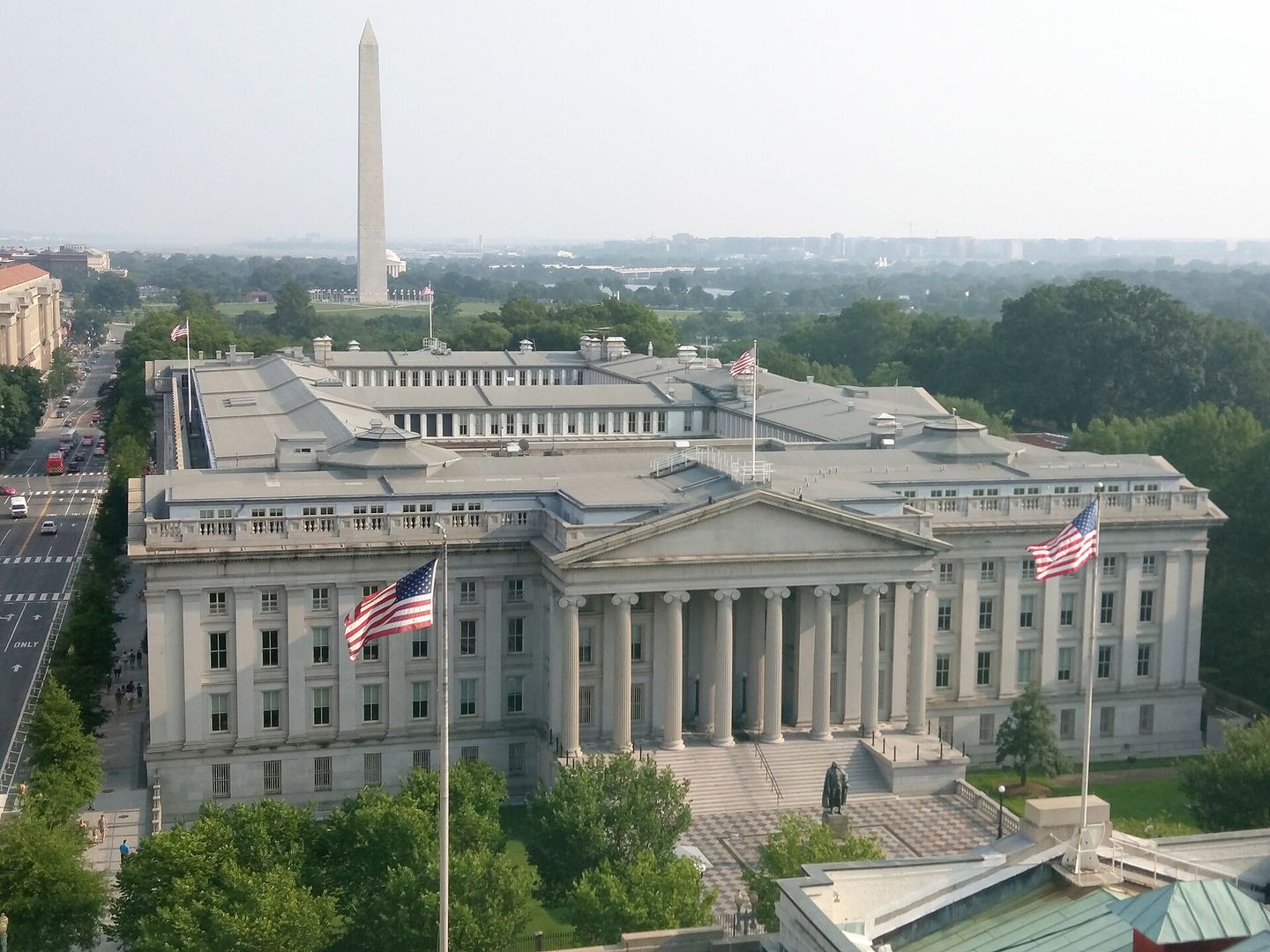 The US Treasury Building from the air, the Washington Monument standing beyond it.